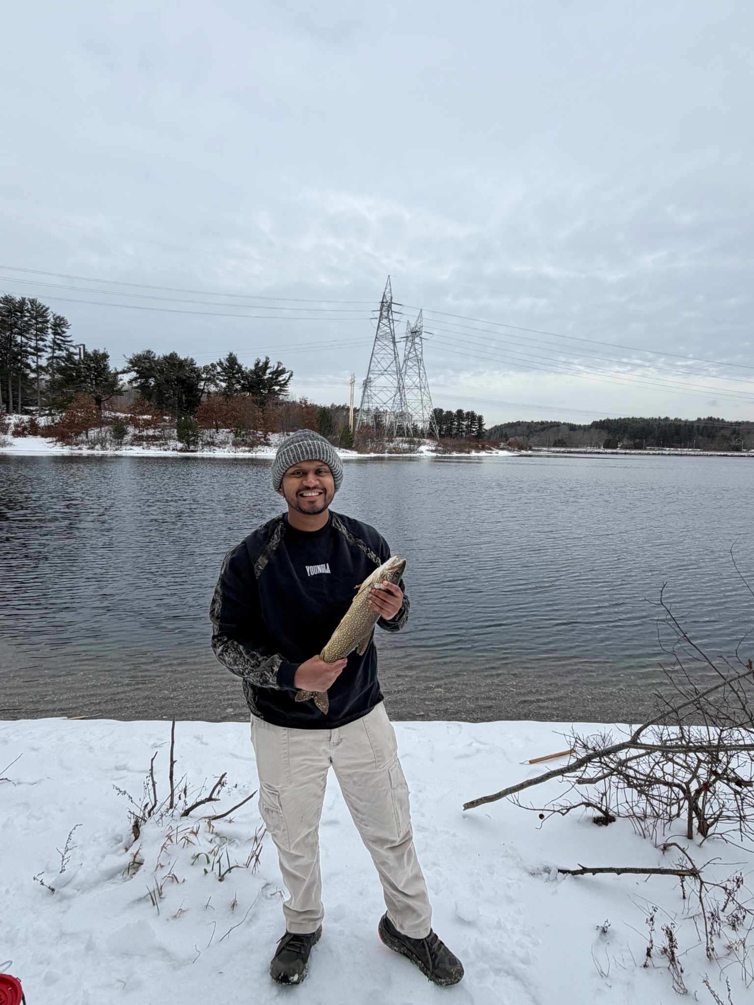 Ripan holding a fish beside a snowy lake